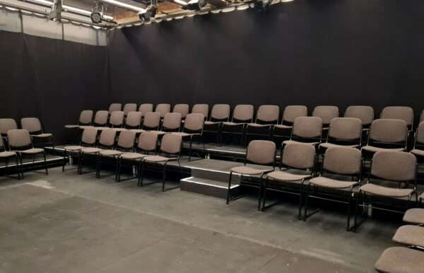 Rows of Chairs on a raked seating bank in a Black Box Theatre. 