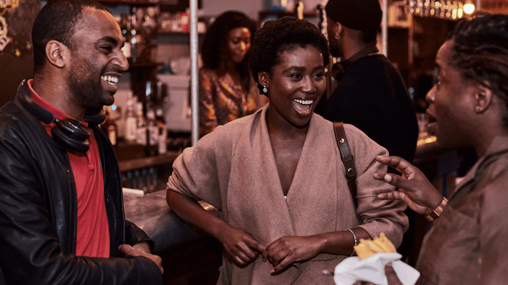 A group of people of colour chatting together and smiling in a bar.