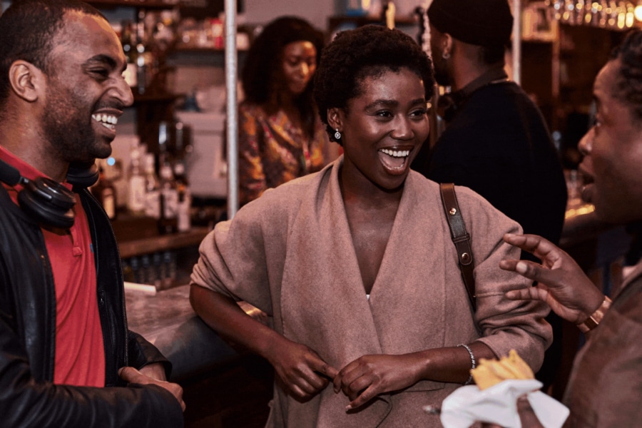 A group of people in a bar chatting and smiling.