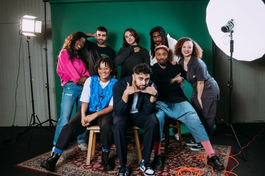group of people sat in front of a green back drop with studio lights in frame.