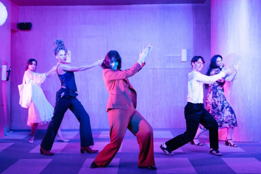 group of people performing on stage, they are holding their arms too the right up in the air clapping.