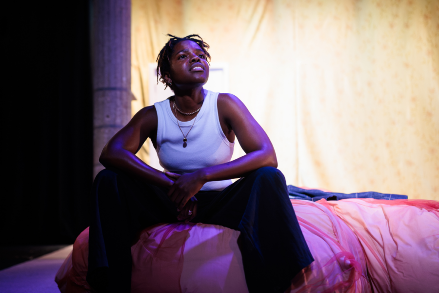 Production photo: Francesca Amewudah-Rivers sits on a mattress.